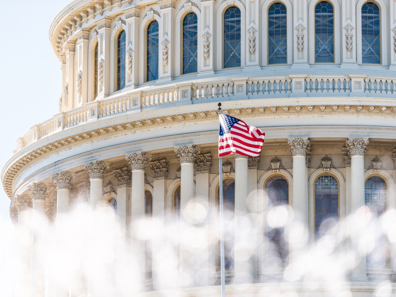US Congress dome closeup with background of water fountain splashing, American flag waving in Washington DC, USA closeup on Capital capitol hill, columns, pillars, nobody